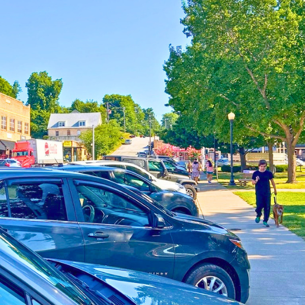 Cars parked along the courthouse square as pedestrians walk through downtown Harrison, Arkansas, on a sunny day.